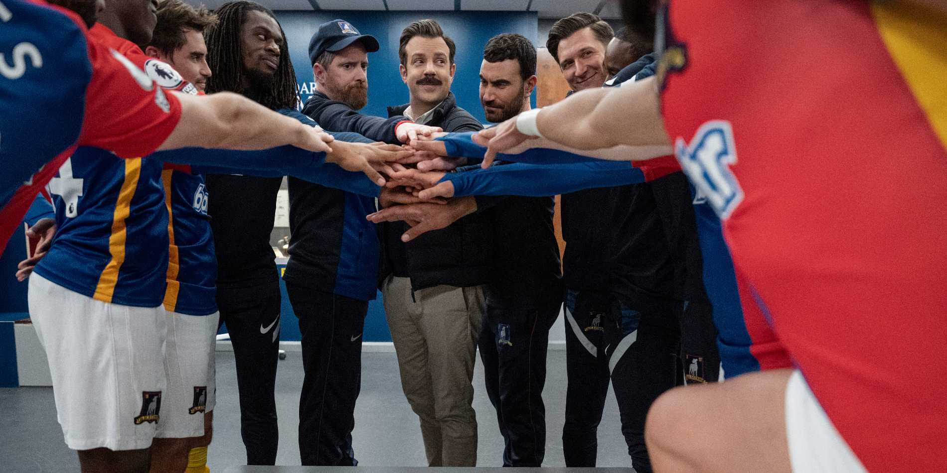 Игроки "AFC Richmond" поднимают руки в раздевалке в сериале "Тэд Лассо"