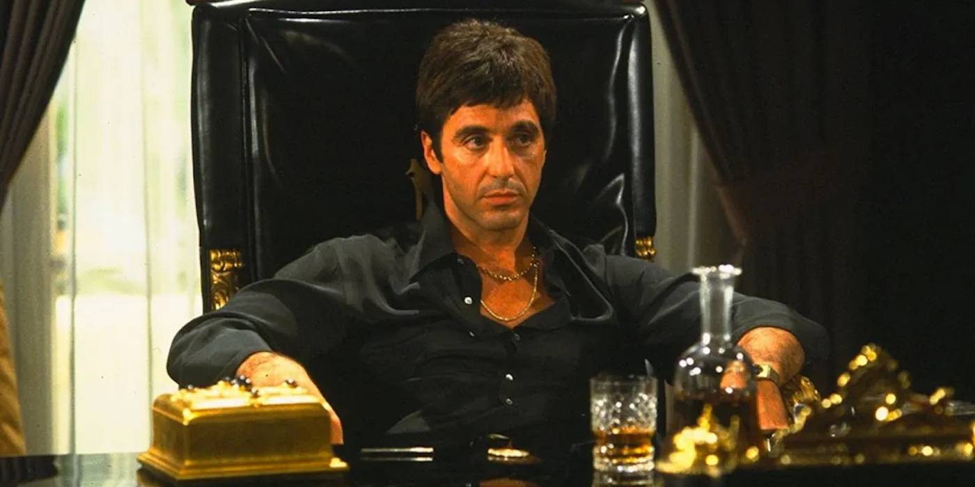 Аль Пачино в роли Тони Монтана сидит на троне в своем кабинете с напитком перед ним в фильме "Скарфэйс"
