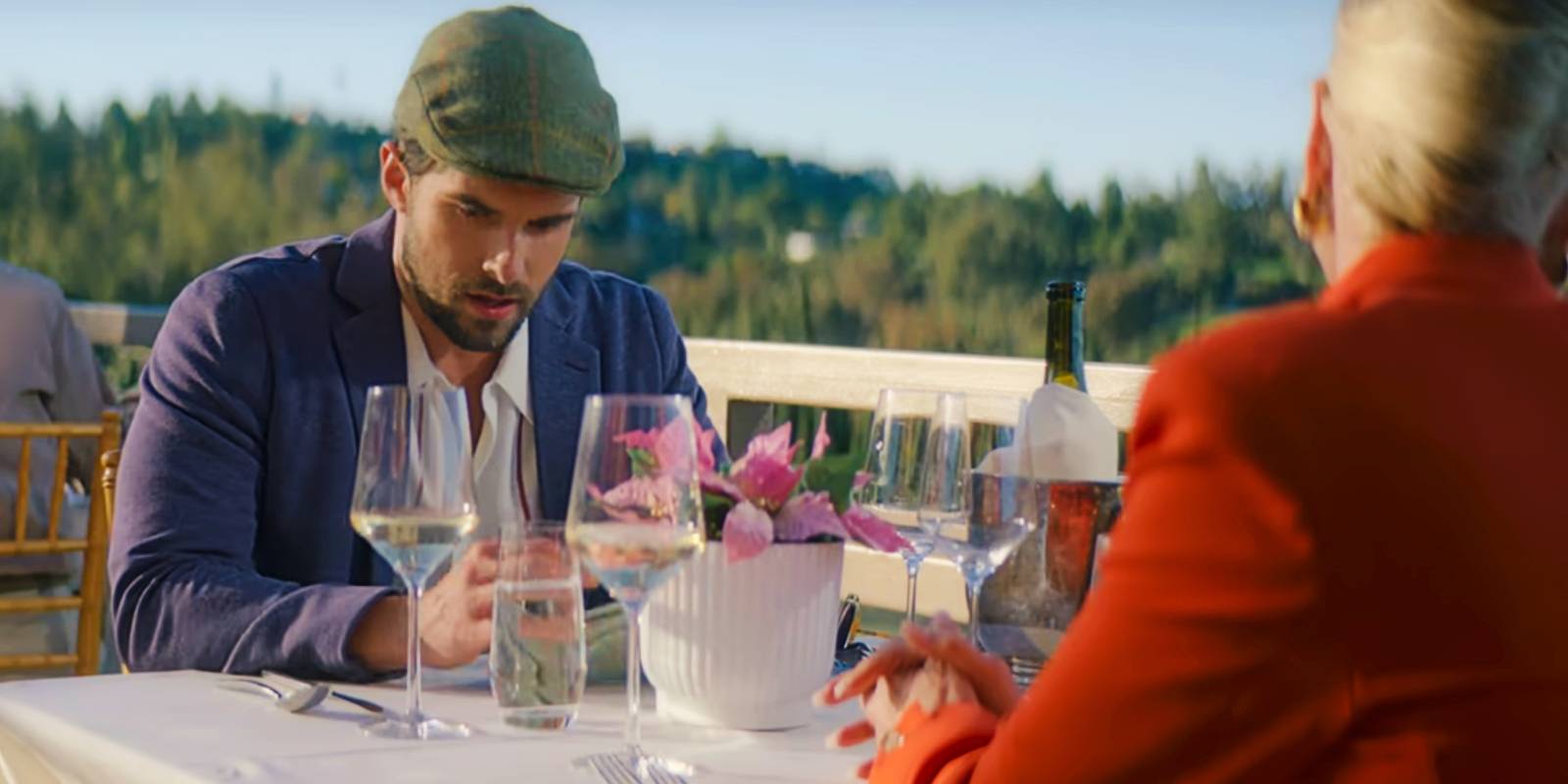 Картер смотрит вниз, сидя за столом на улице с Марго в Holiday in the Vineyards