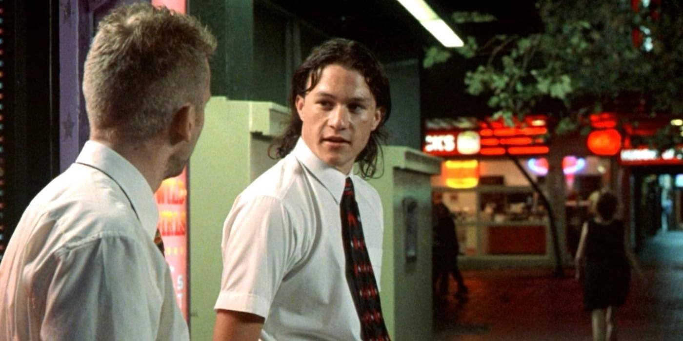 Хит Леджер, разговаривающий на улице в рубашке и галстуке.