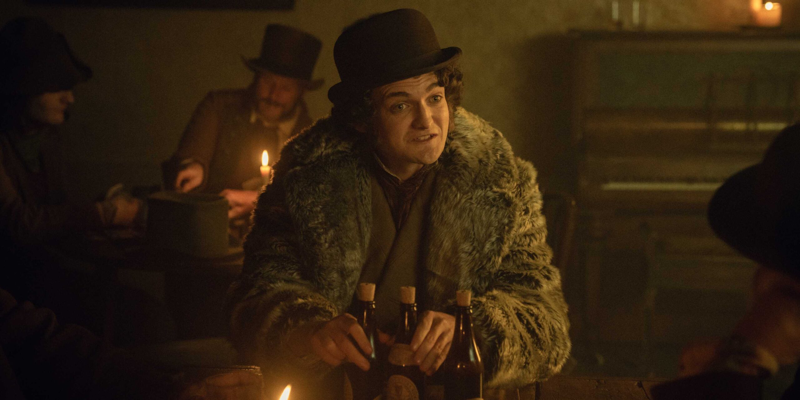 Джак Глисон в роли Байрона Хедса, сидящего и держащего несколько бутылок в Доме Гиннеса