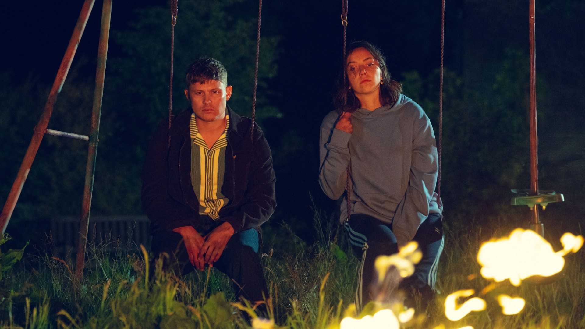 Джон Поинтинг в роли Эша и Мейв Кертье-Лилли в роли Ди Ди сидят вместе на качелях.