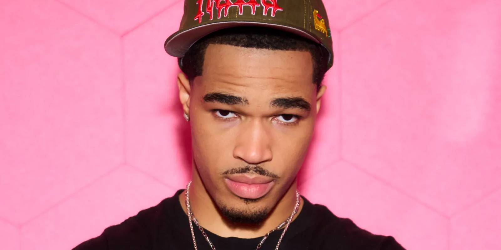 Стример plaqueboymax позирует перед розовым фоном.