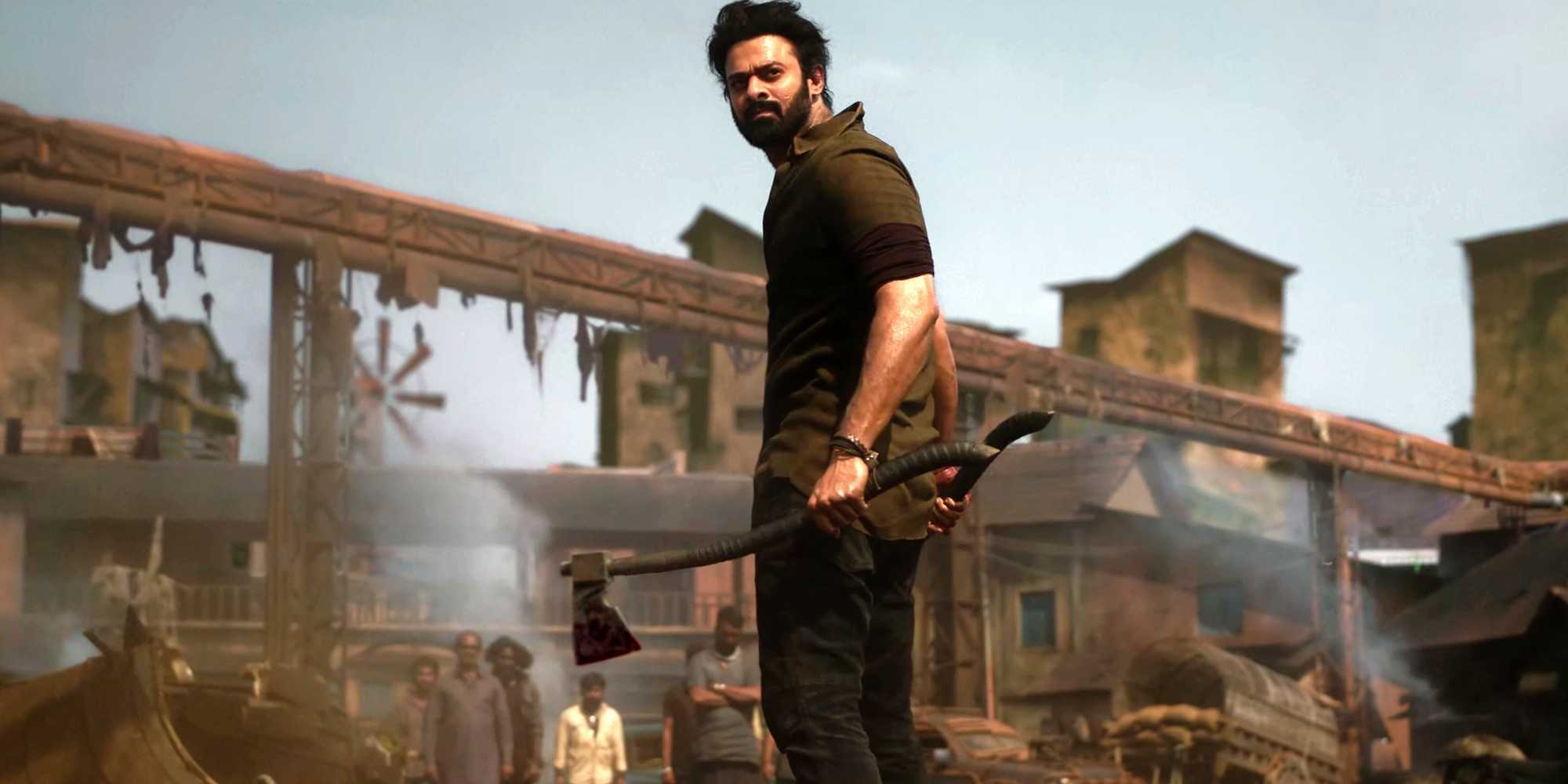 Прибас в роли Салаара, стоящий среди руин, держа в руках топор и оглядывающийся назад в фильме "Salaar Part 1 - Ceasefire".