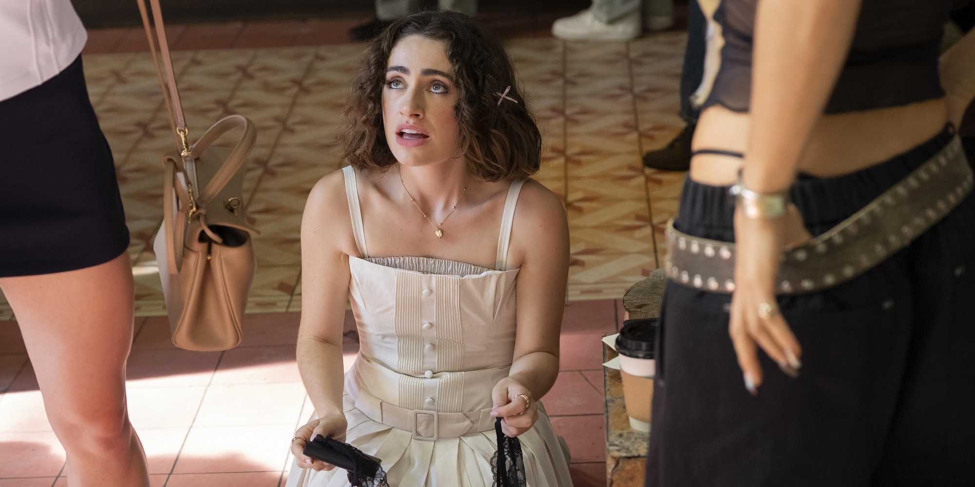 Рачел Сеннот в роли Майи в сериале I Love LA, одетая в белое платье и склонившаяся на пол.