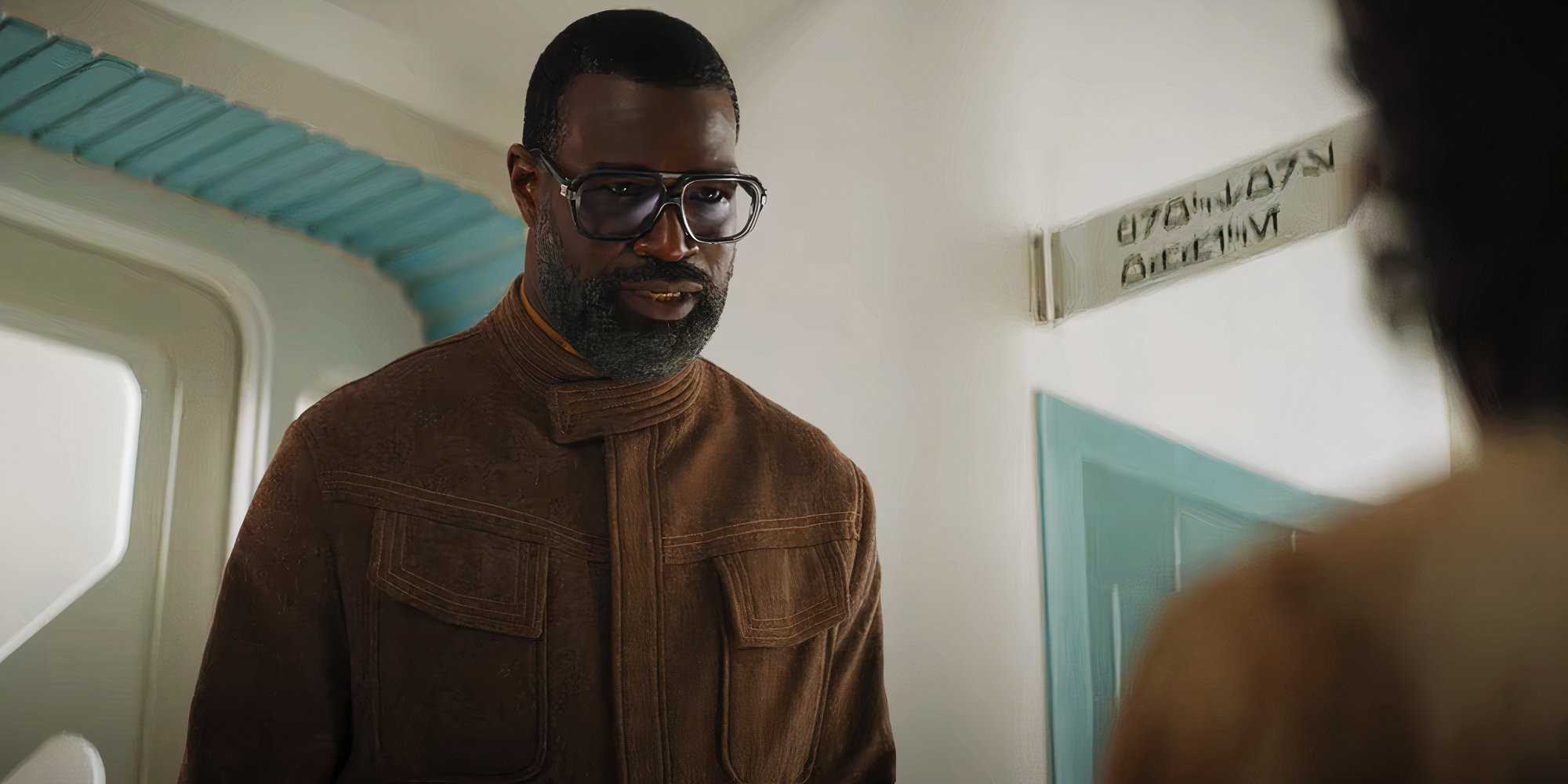 Вендл (Тунде Адебимпе) смотрит серьезно на Вима за пределами кабинета прораба.