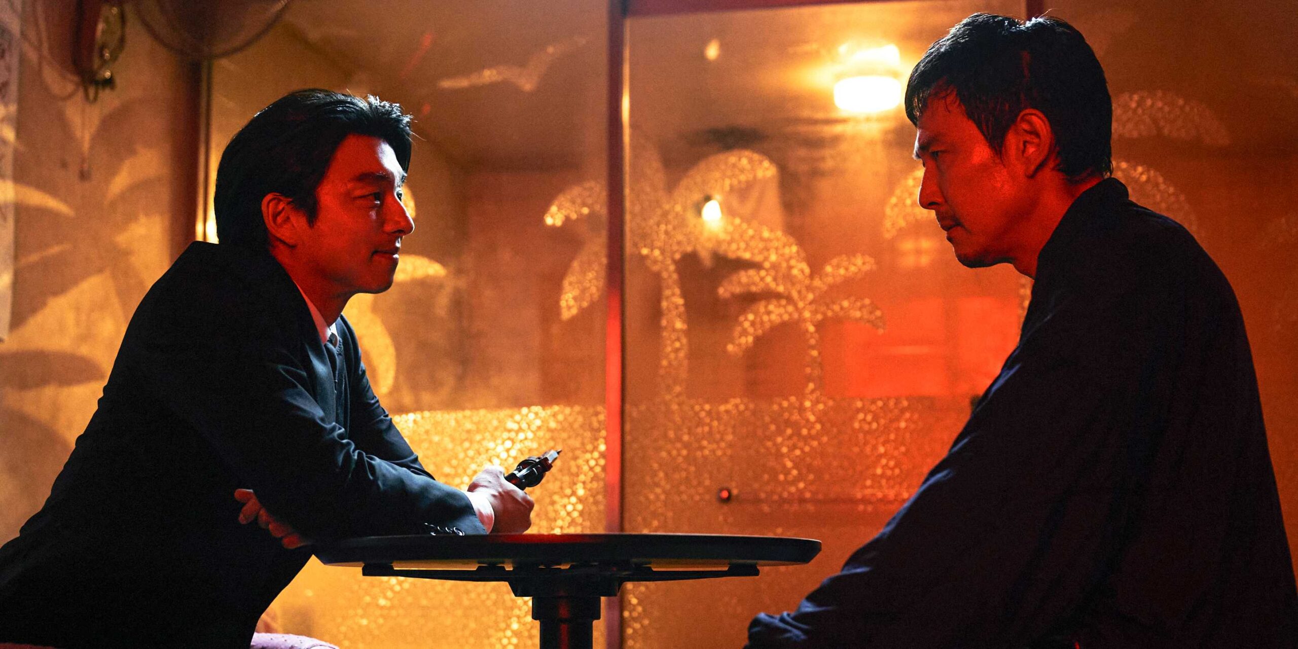 Продавец улыбается и держит пистолет напротив Ги-хуна, который уверенно участвует в "Игре в кальмара" 2 сезона