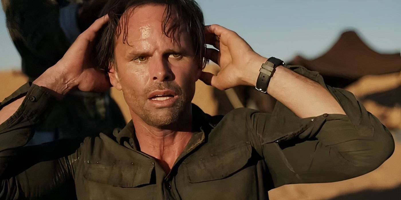 Волтон Гогинс в роли Натана Миллера, держащего голову руками, с выражением беспокойства в сериале "Deep State"