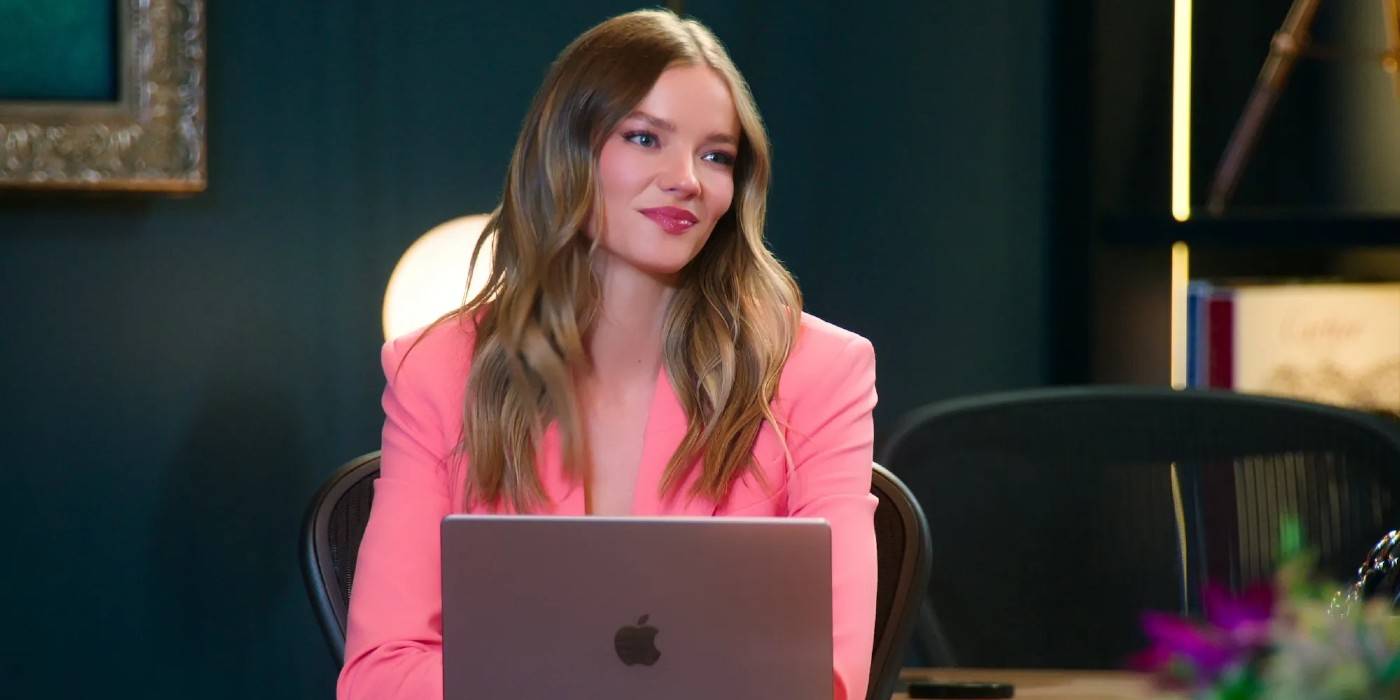 Аланна Голд из 8-го сезона *Selling Sunset*, сидя за столом в розовом пиджаке.