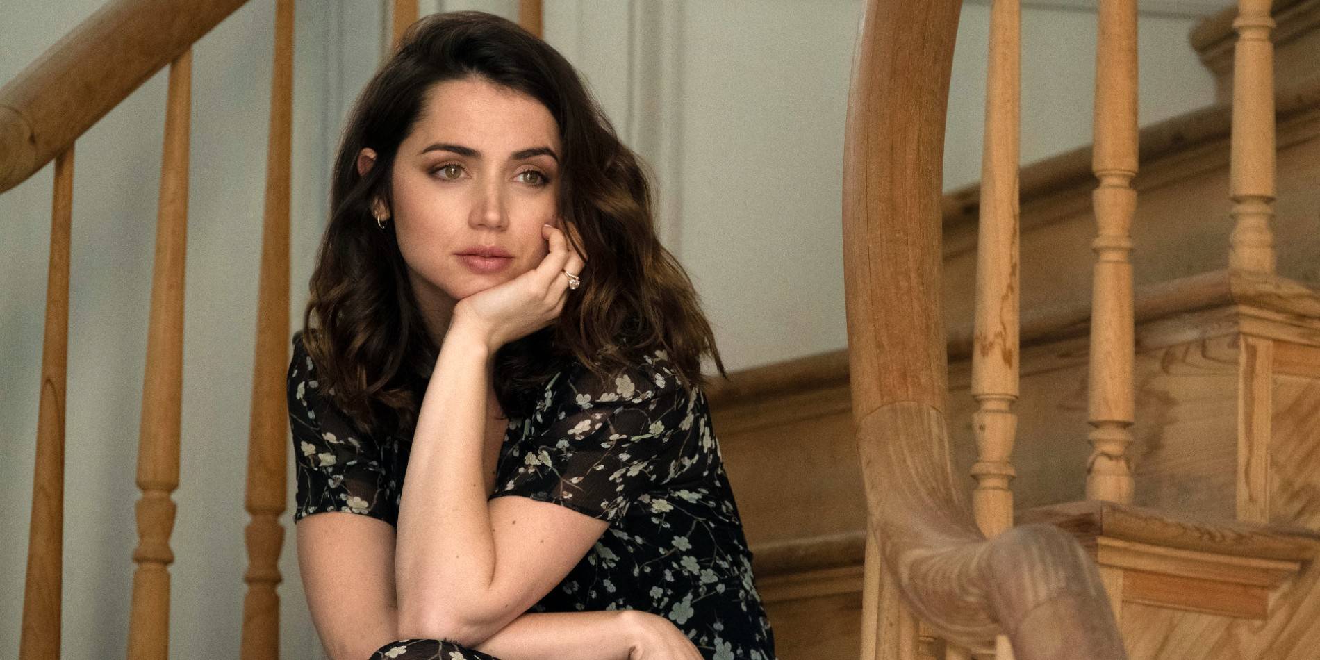 Ана де Армас в роли Мелинды, сидящей на лестнице и смотрящей в фильме "Deep Water".