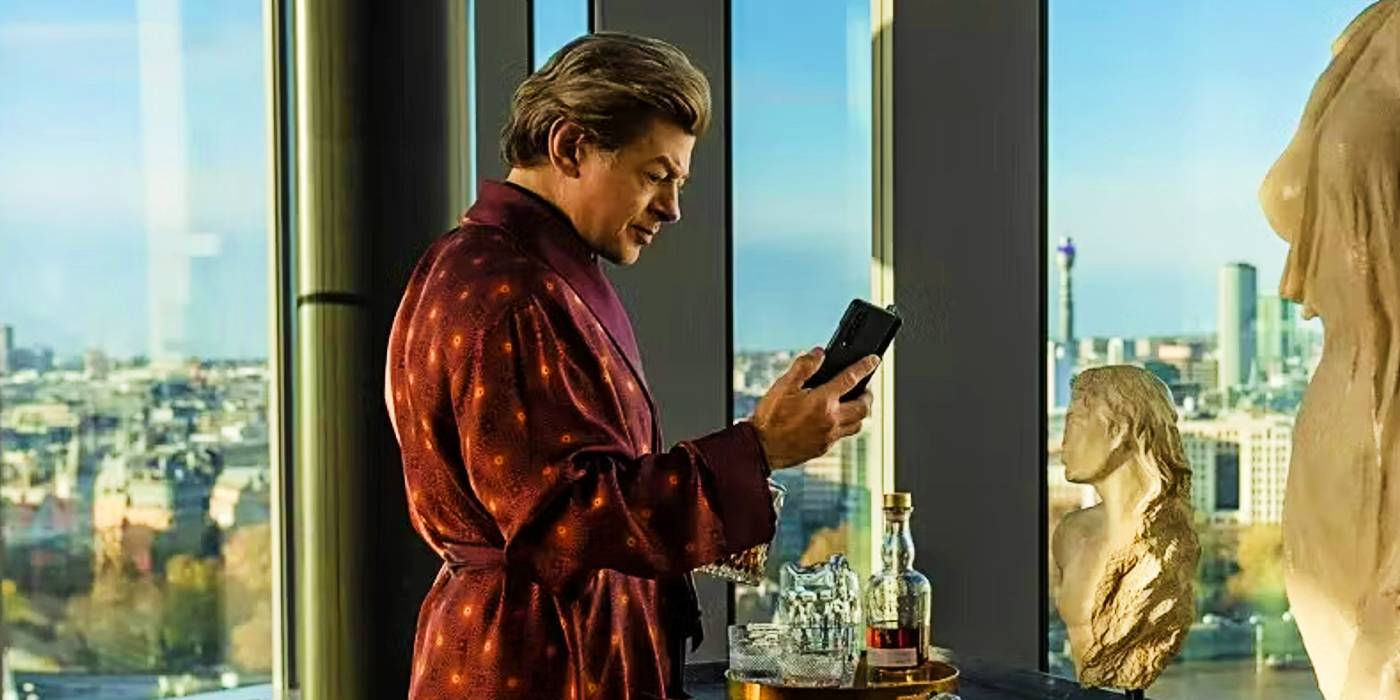 Энди Серкис в красном одеянии, смотрящий в телефон в фильме "Лютер: Павший Солнце"