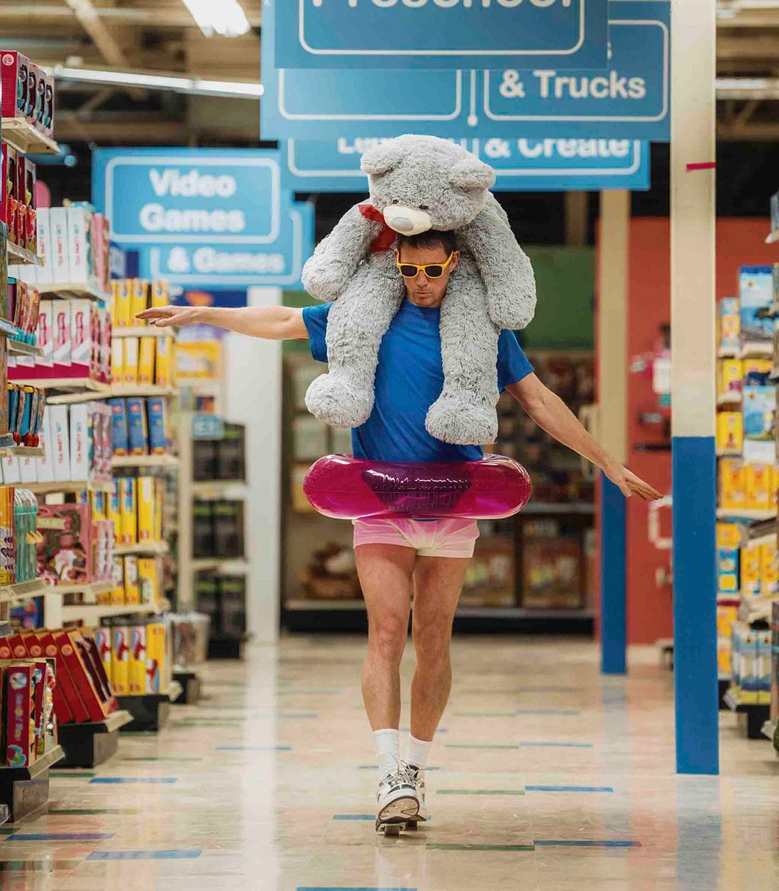 Ченнинг Татум в роли Джеффа, идущего по проходу с плюшевым мишкой и плавающим пончиком в Roofman-1