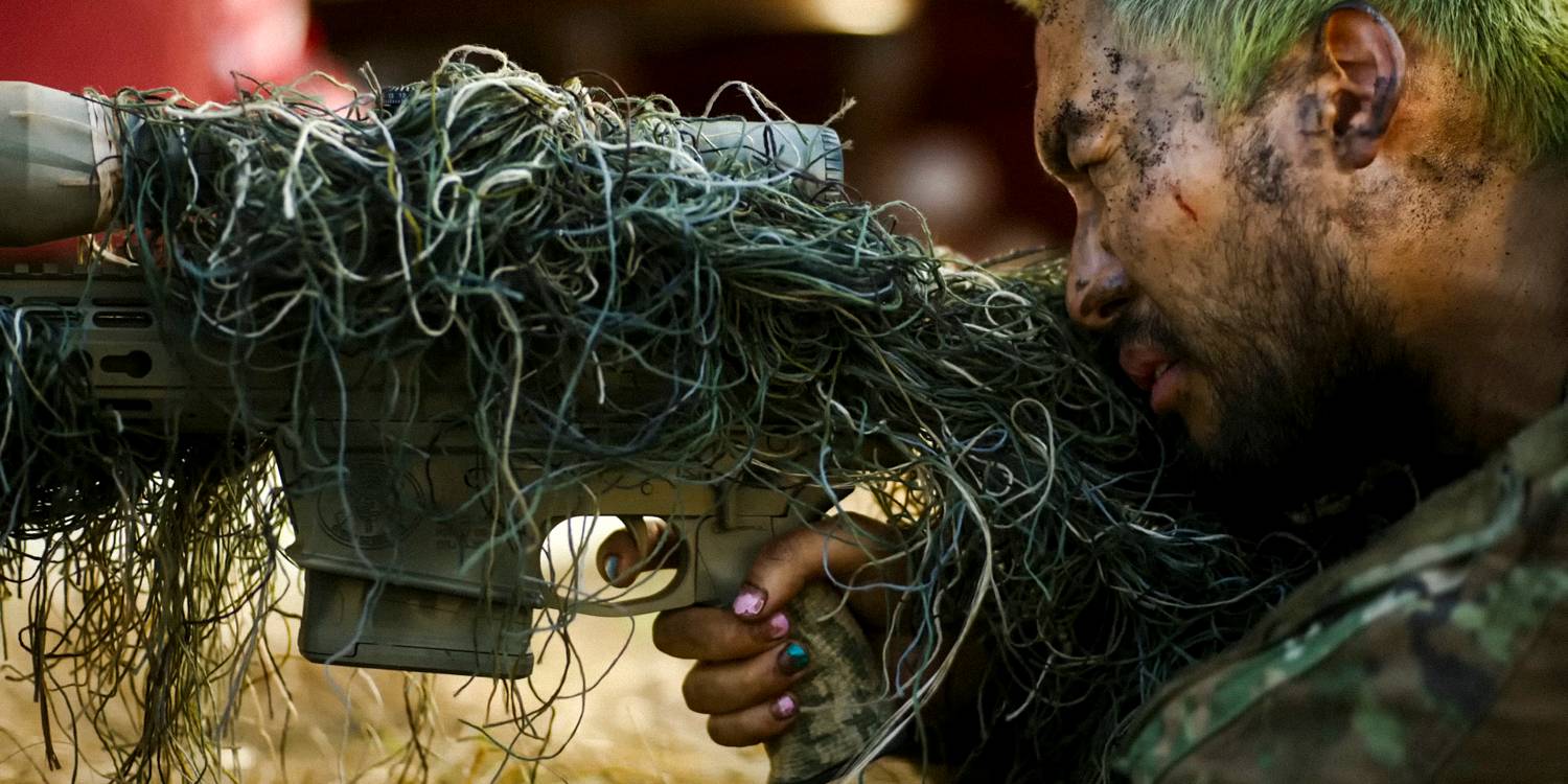 Джин Ха в роли снайпера с винтовкой, покрытой мхом для маскировки в фильме "Гражданская война" 2024