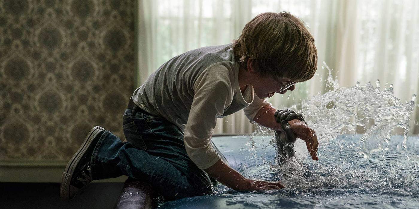 Джалин Хайллард в роли Дэвида Глатцеля в фильме "Призраки: Дьявол заставил меня это сделать", кричащий над водой, когда рука тянется, чтобы схватить его запястье