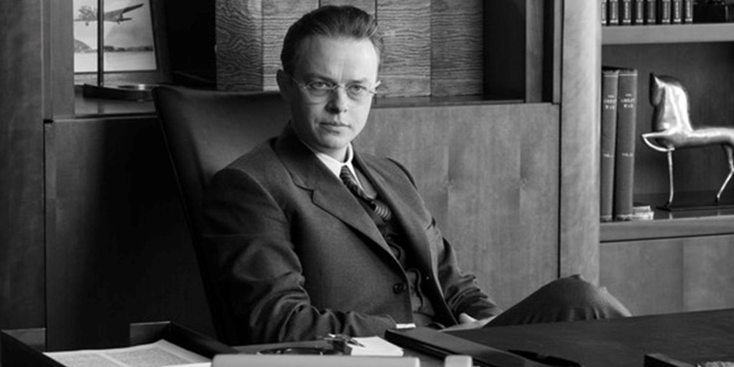 Дэн Де Хун сидит за столом в "Оппенгеймере"