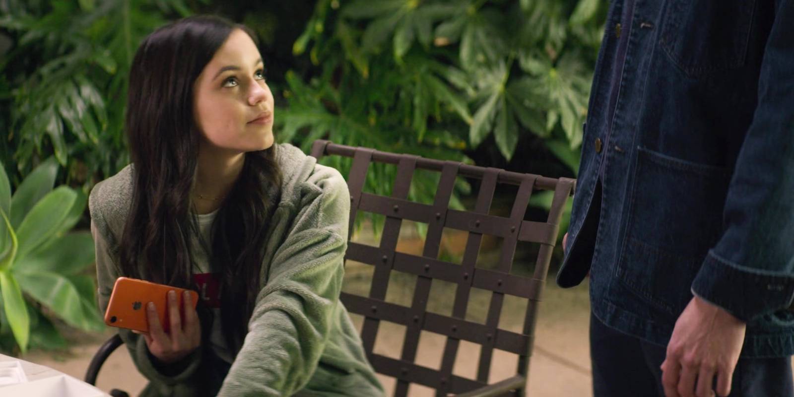 Элли Алвес держит телефон, глядя на Джо в сериале *You*