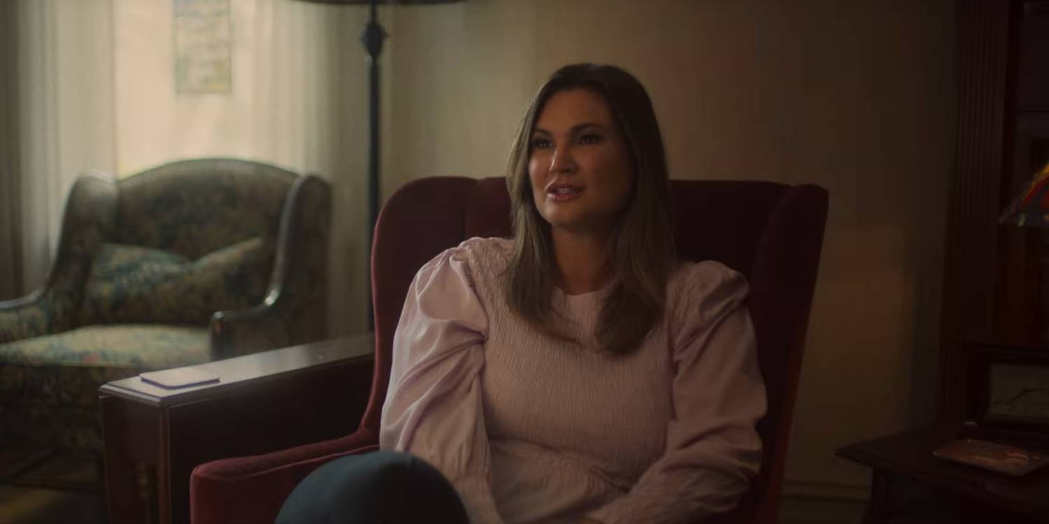 Кини сидит на стуле в светлой розовой рубашке с объемными рукавами в Hell Camp: Teen Nightmare.