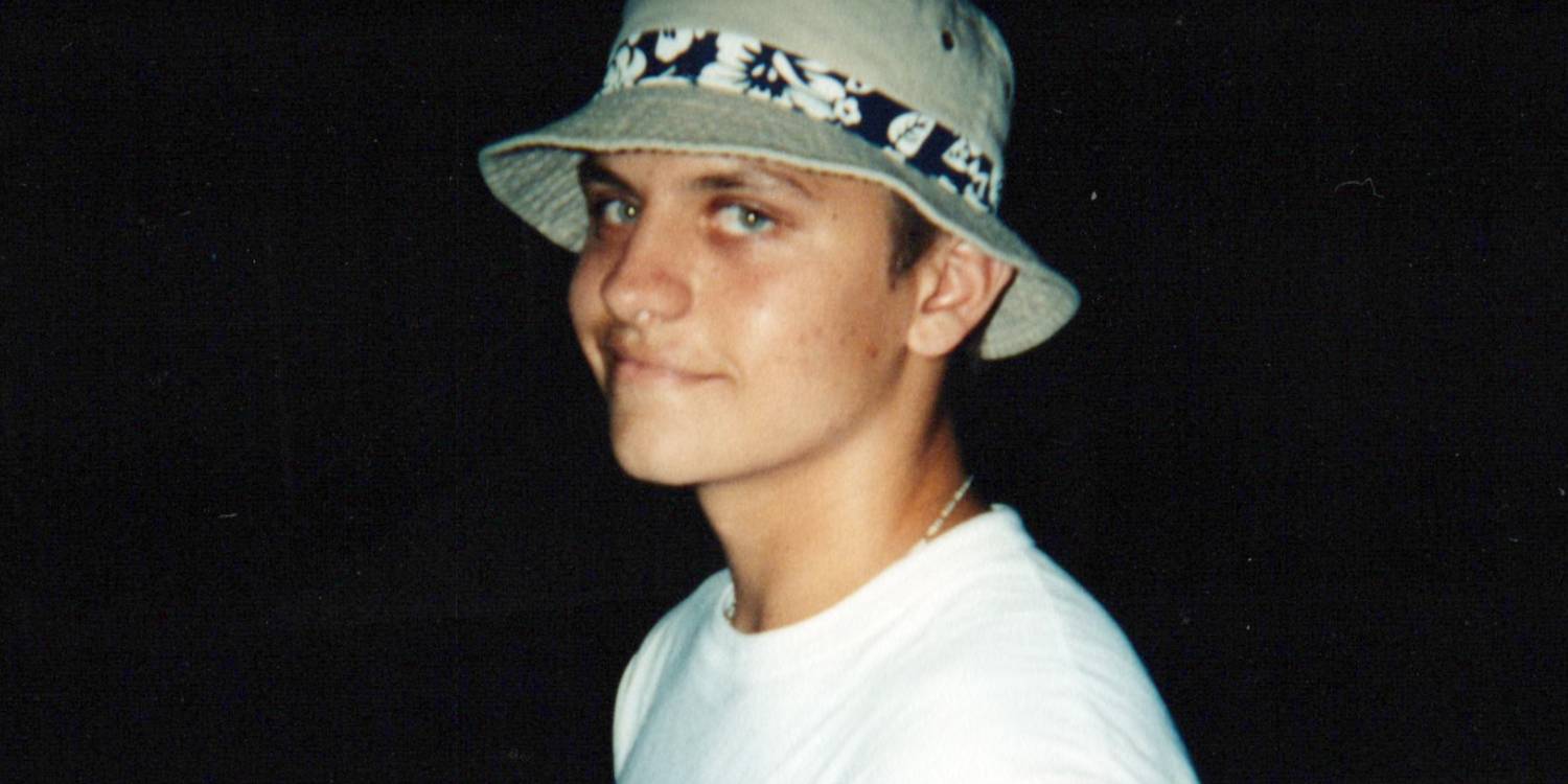 Подросток Курт ухмыляется, одетый в белую футболку и шляпу в Hell Camp: Teen Nightmare.