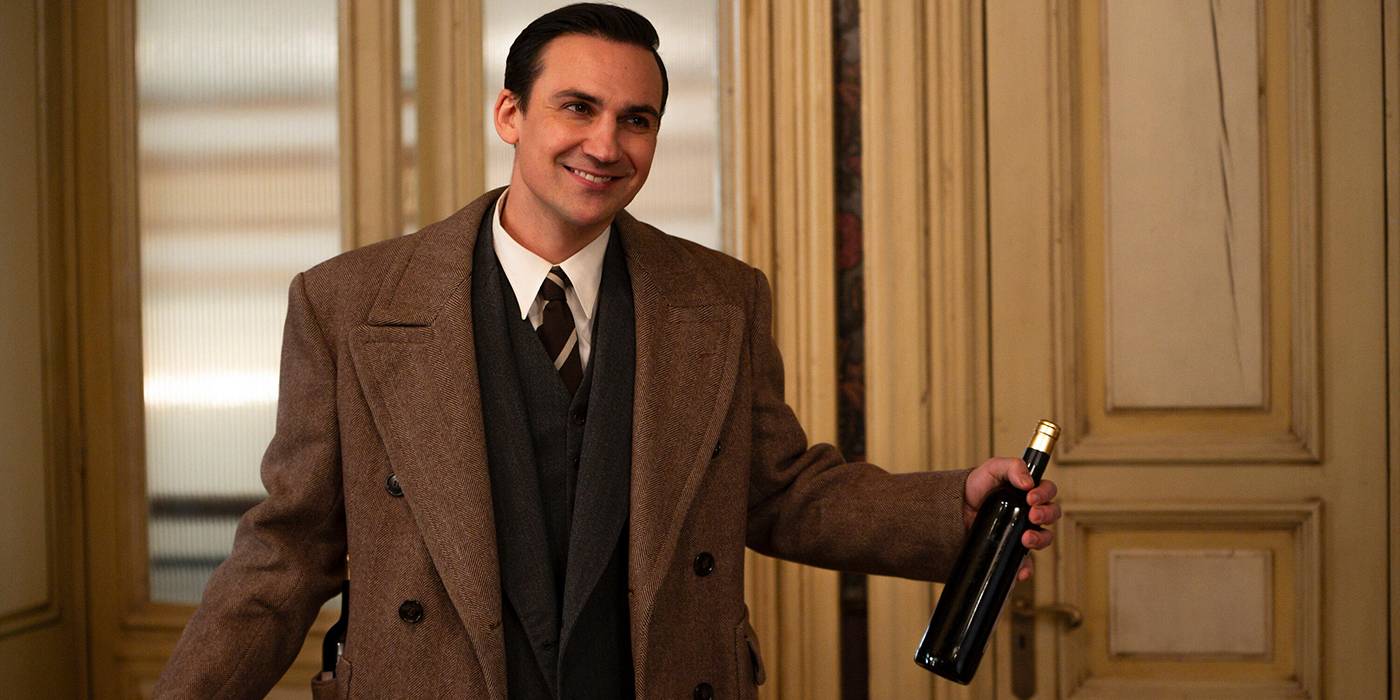 Генек, сыгранный Хенри Ллойд-Хьюз, несет вино в *We Were the Lucky Ones*