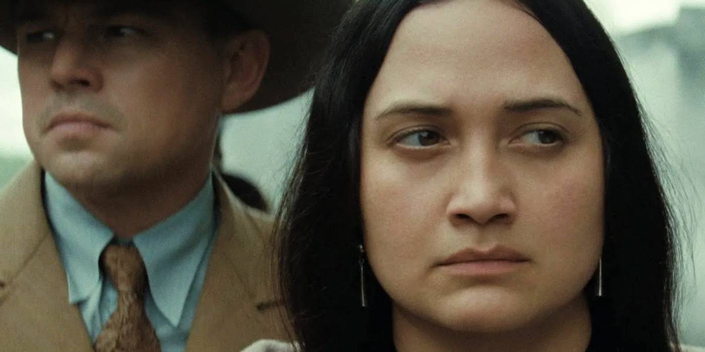 Мэри выглядит сердитой, а Эрнест стоит за ней в фильме "Убийцы из "Цветов".