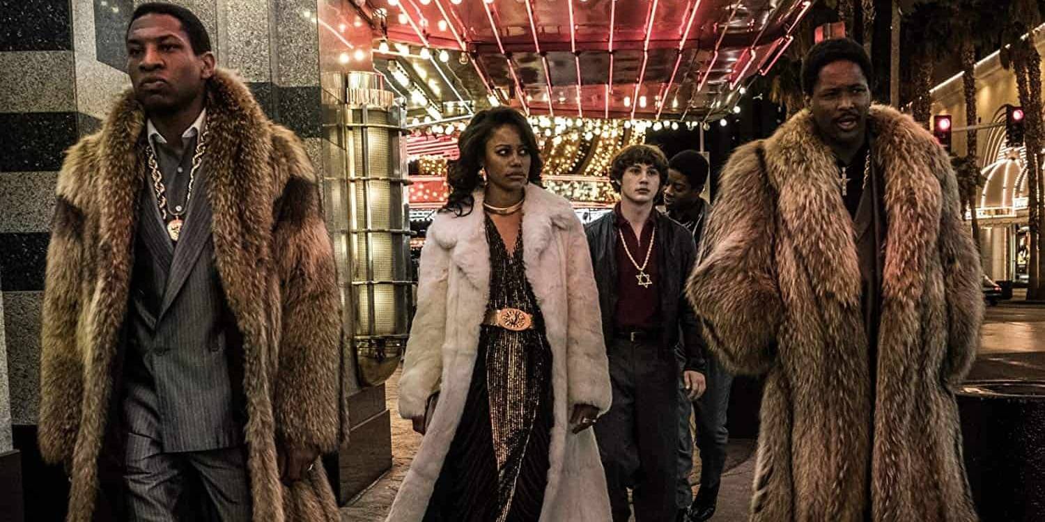 Джонатан Мейорс в роли Джонни Карри, идущего по улице в меховом пальто, окруженный своей свитой в фильме "White Boy Rick"