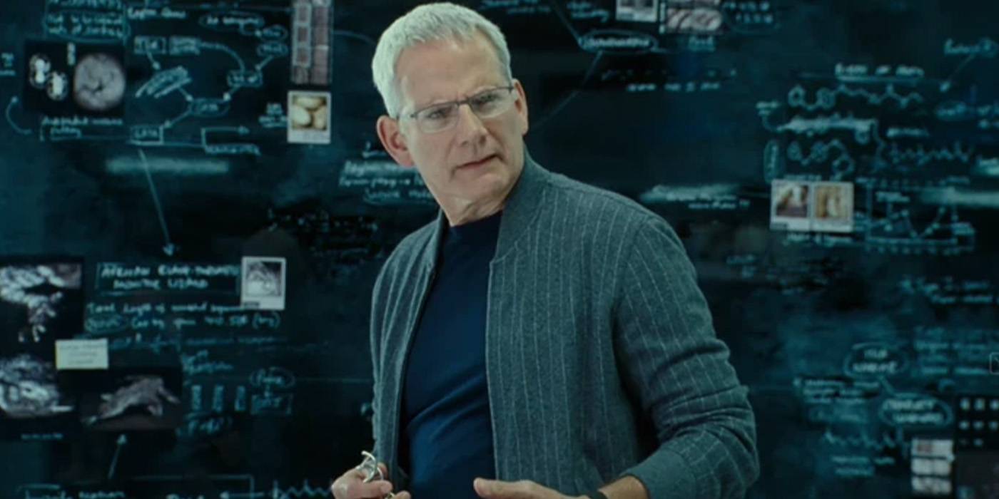 Кампбелл Скотт в роли Левиса Додсона из *Jurassic World Dominion*, стоящий перед доской с заметками