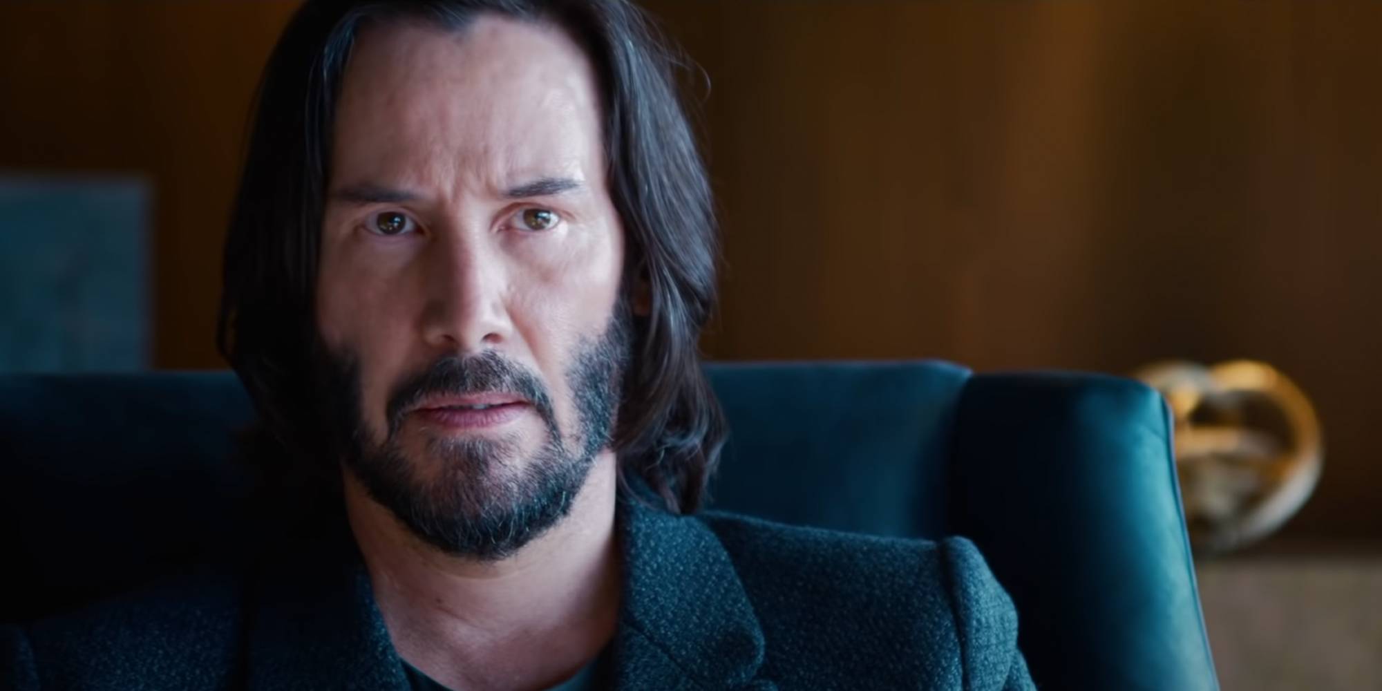 Нео сидит на кожаном кресле в фильме "Матрица: Воскрешение"