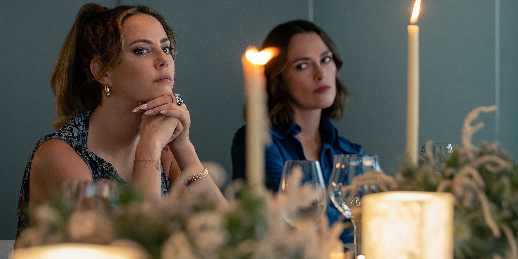 Кейра Найтли в роли Ло, смотрящей с осуждением на Каю Скоделарио в роли Грей за столом в The Woman in Cabin 10