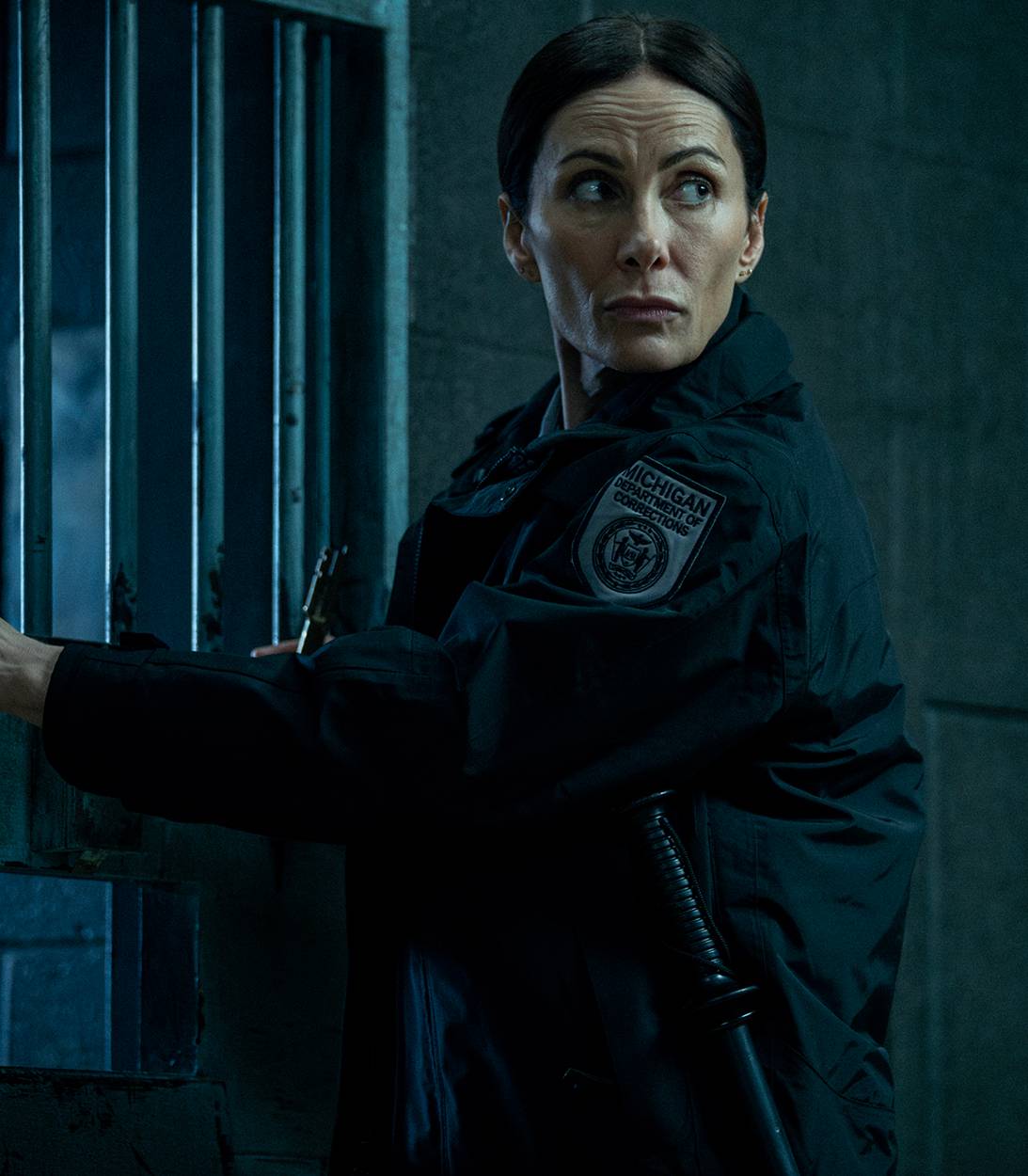 Cindy, сыгранная Лаурой Бененти, с любопытством оглядывается через плечо, держась за дверь тюремной камеры в 4 сезоне сериала "Mayor of Kingstown"