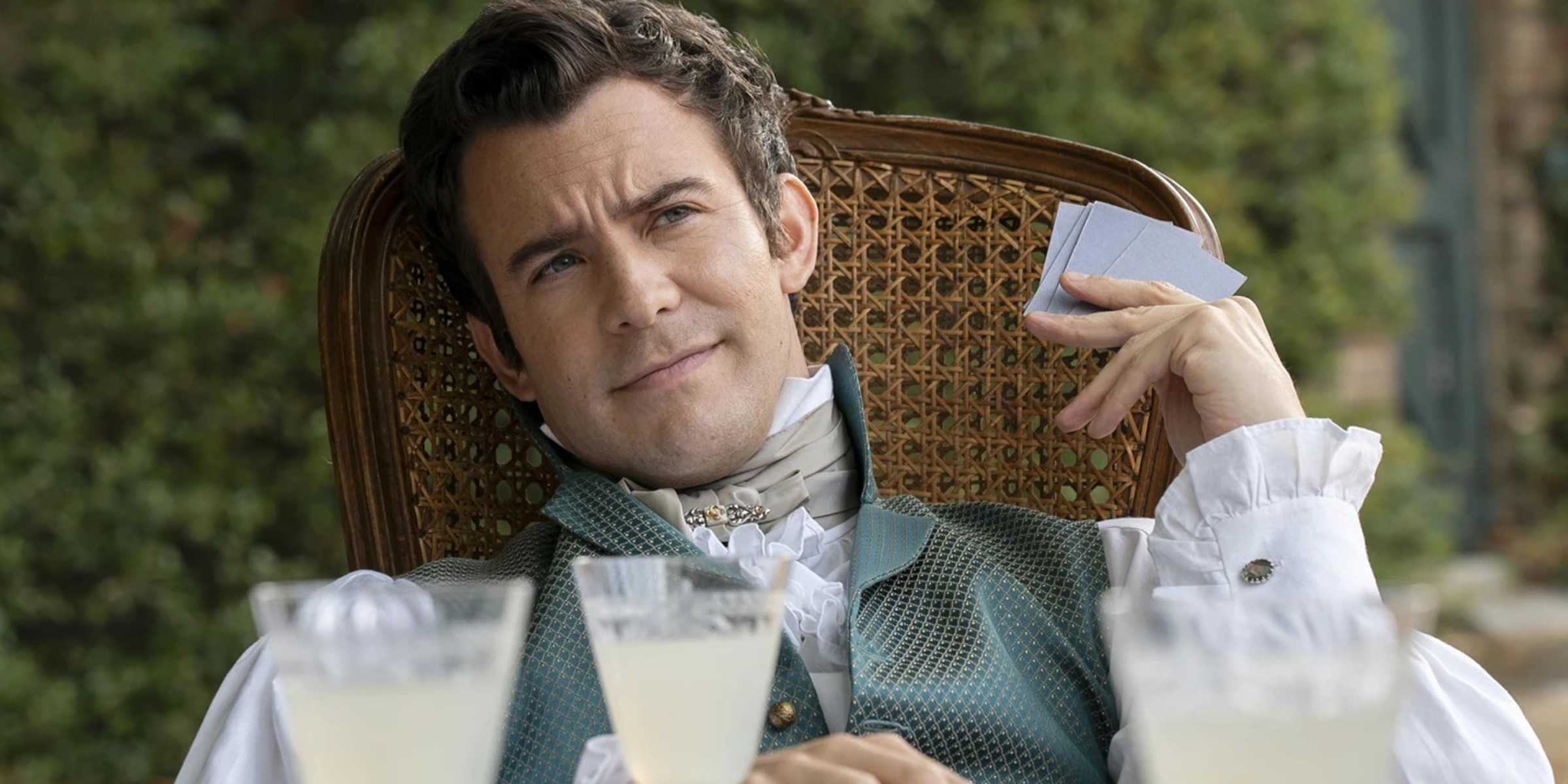 Лук Томпсон в роли Бенджамина Бриджертона, сидящего в кресле и держащего карты