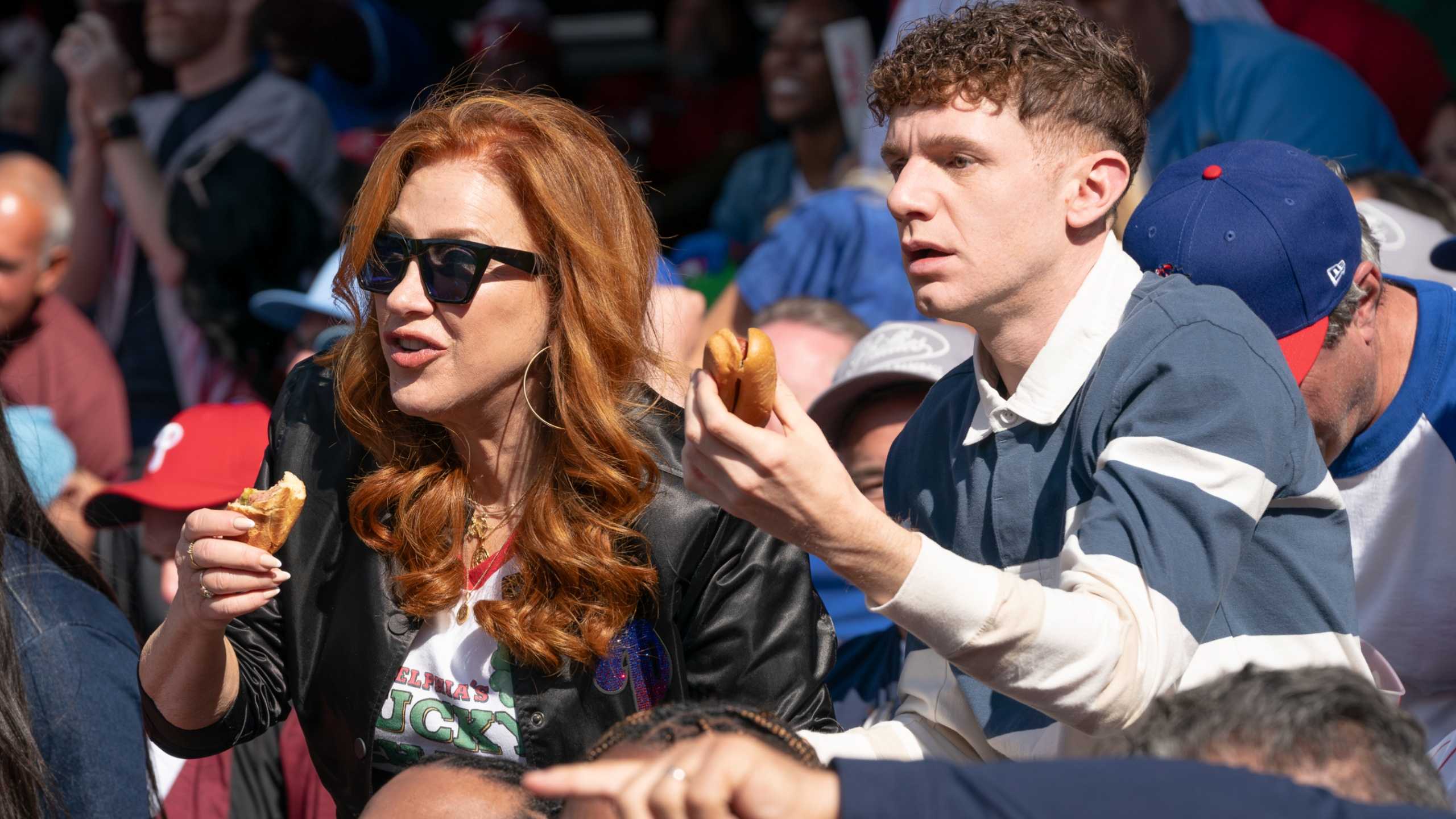 Мелисса (Лиза Эн Уолтер) и Джейкоб (Крис Перфети) едят хот-доги на спортивном матче в Abbott Elementary