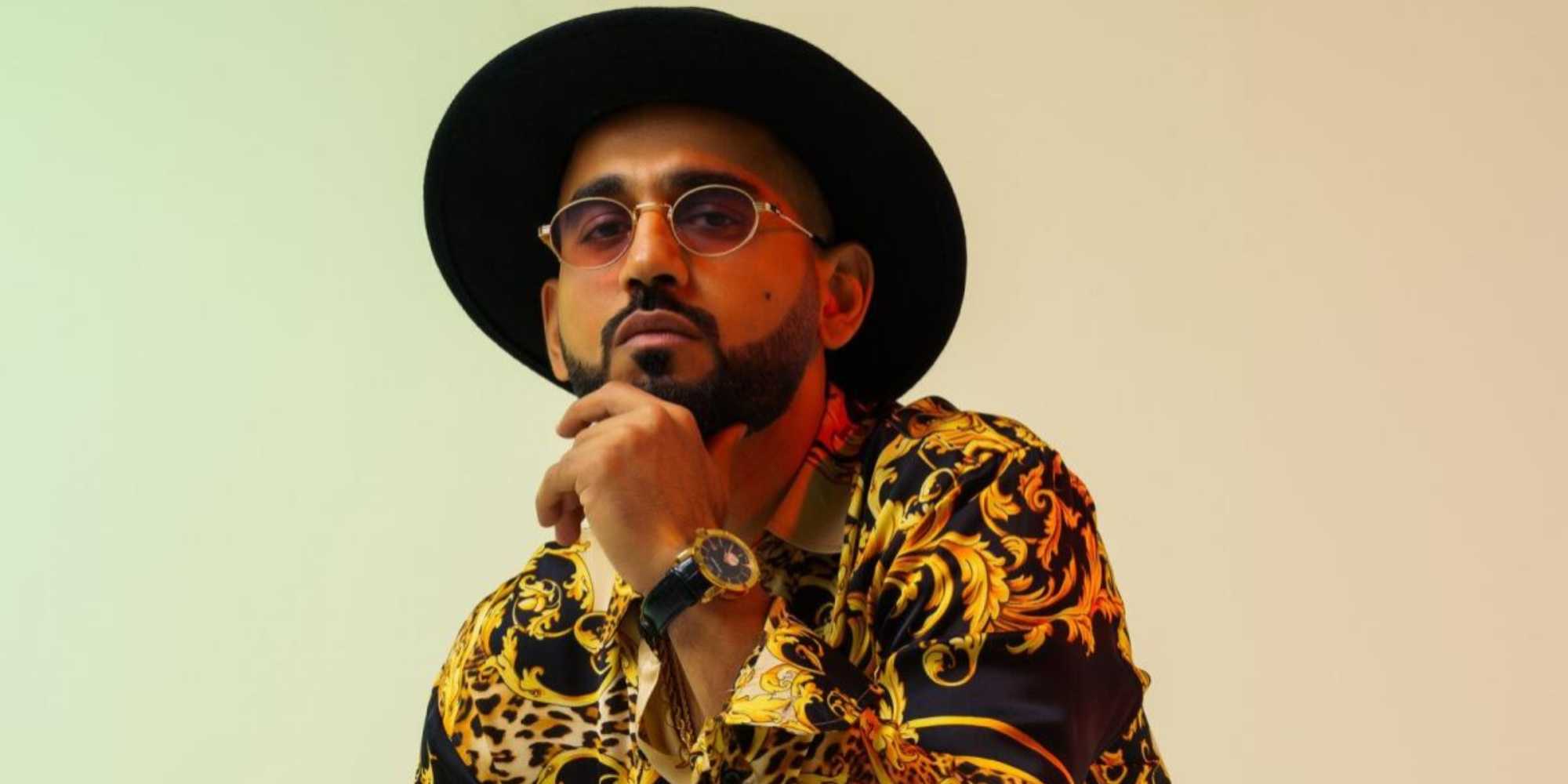 DJ Bliss в черном и золотом костюме Versace с черной шляпой и часами