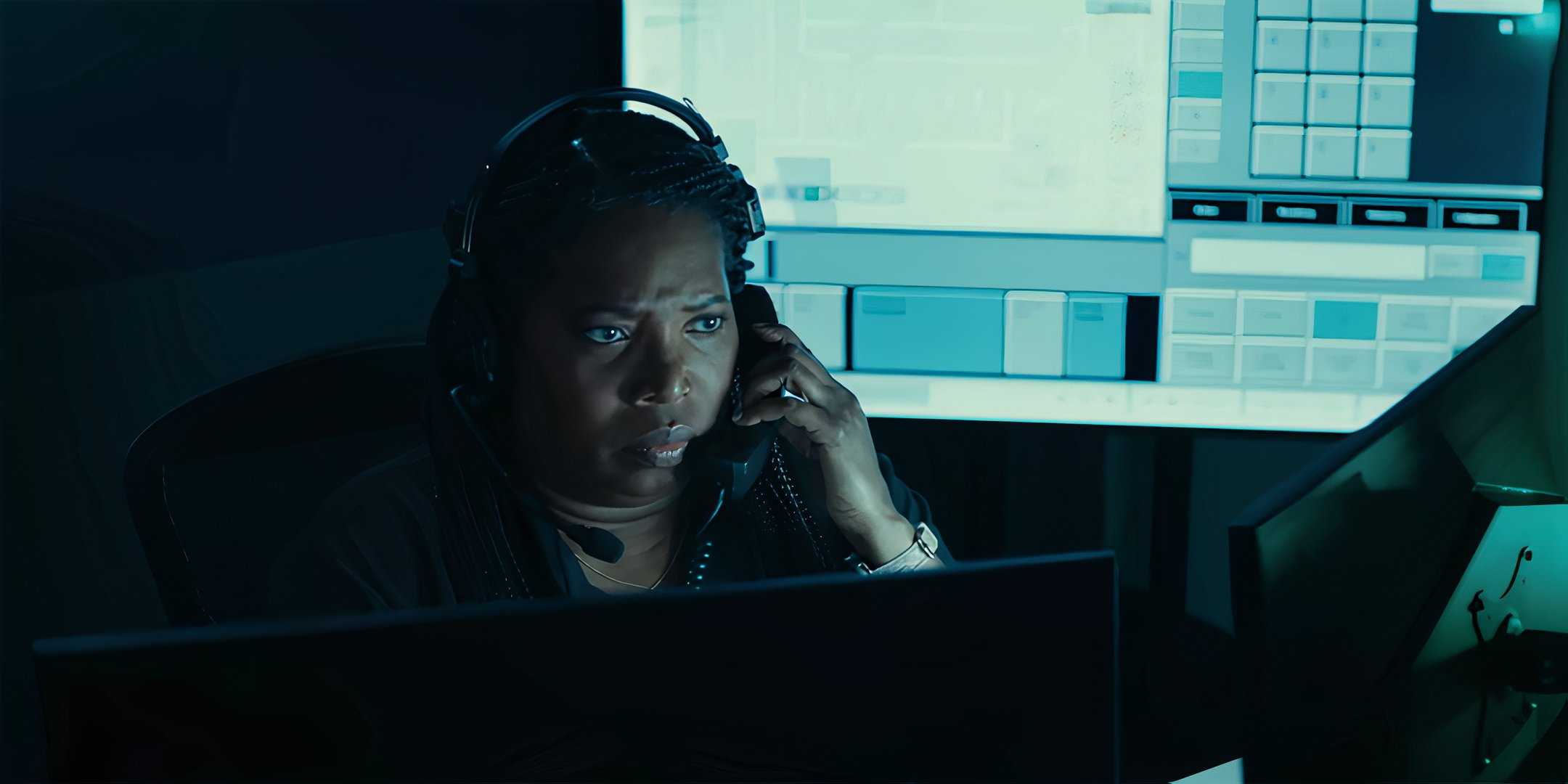 Саида Аррика Экулона в роли Сиси, разговаривающая по телефону и выглядящая серьезно за своим столом в "Amber Alert"