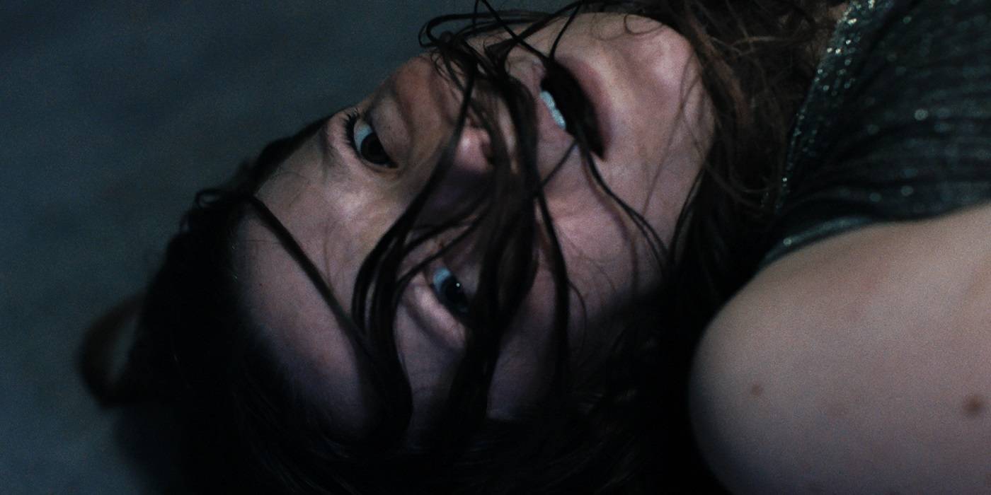 Морфид Кларк в роли Мэуд, лежащей на земле с волосами в лицо, испуганная в фильме "Saint Maud"