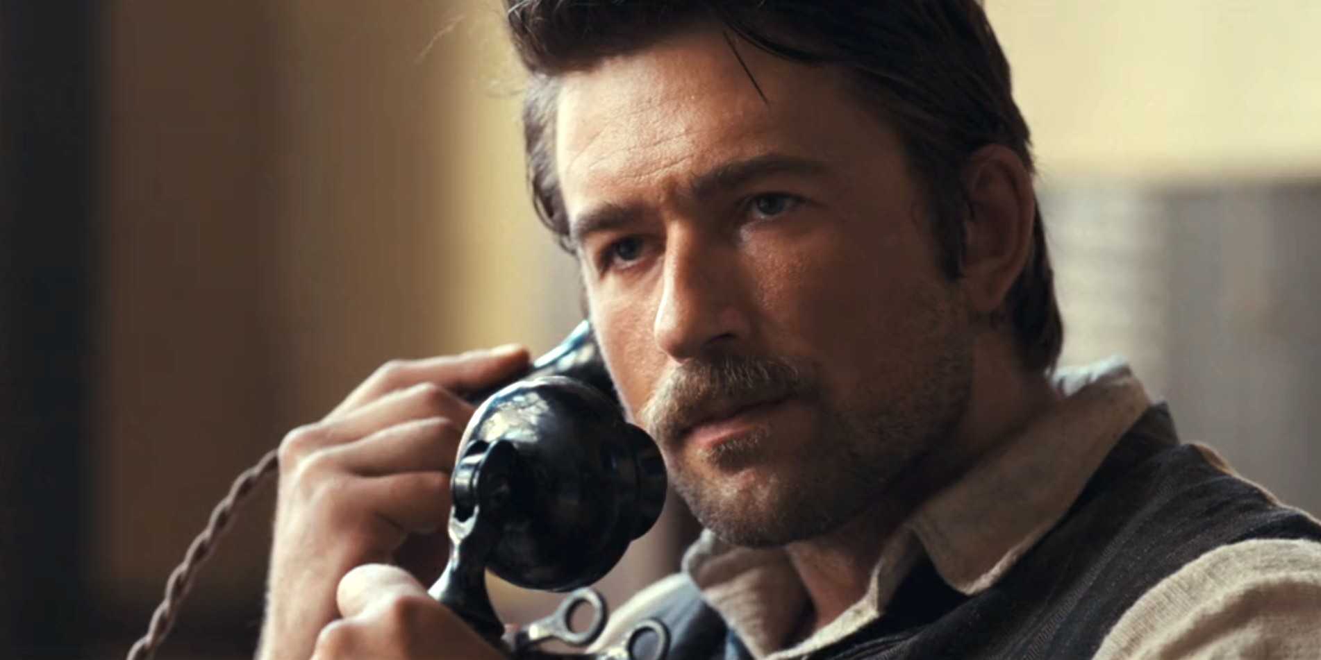 Спенсер Дютт (Брендон Скленар) с сердитым выражением лица, разговаривающий по телефону в 2 сезоне сериала "1923", 5 эпизод