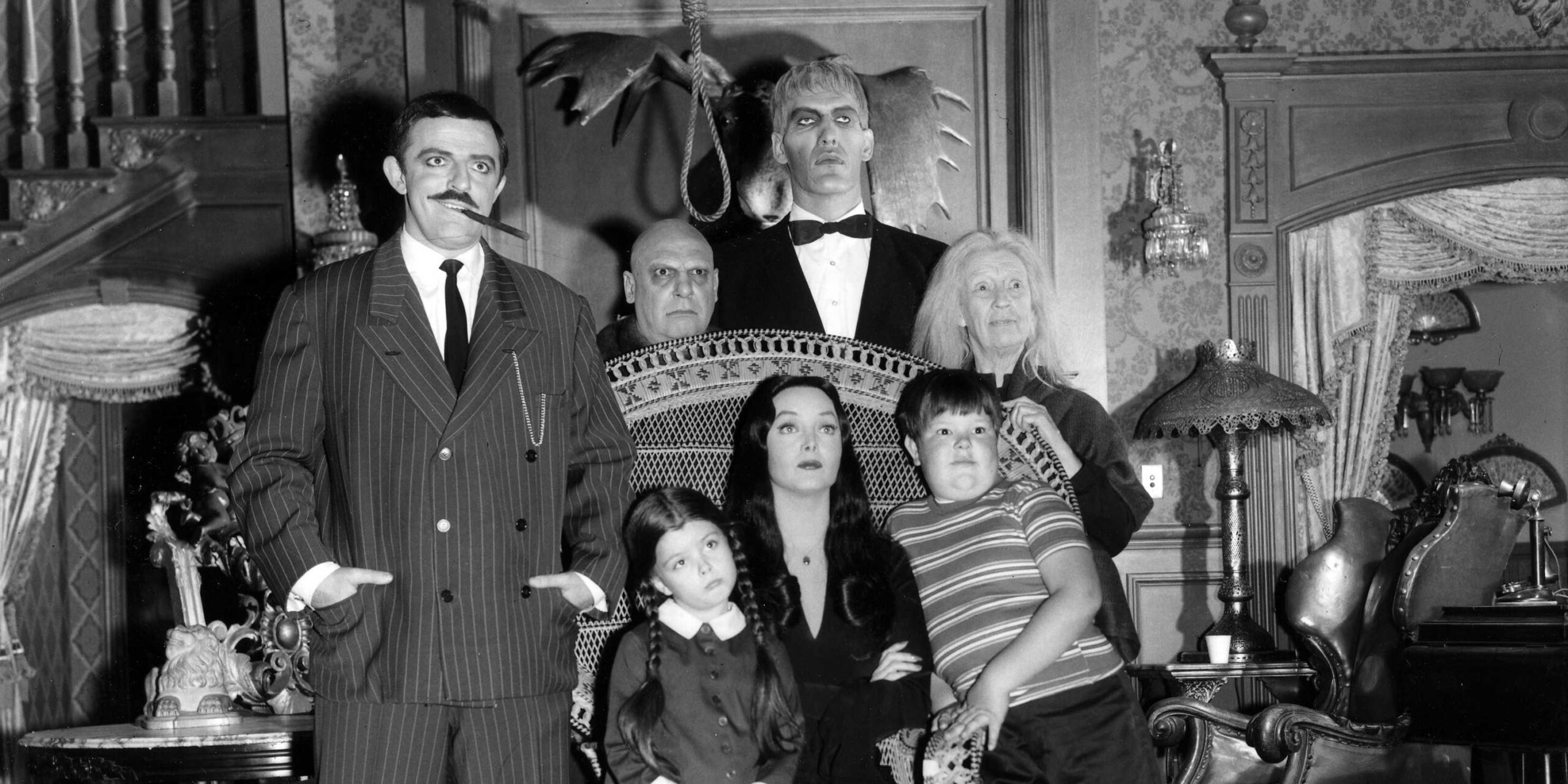 Morticia, Gomez, Uncle Fester, Lurch, Grandmama, Wednesday, and Pugsley pose for a photo in The Addams Family