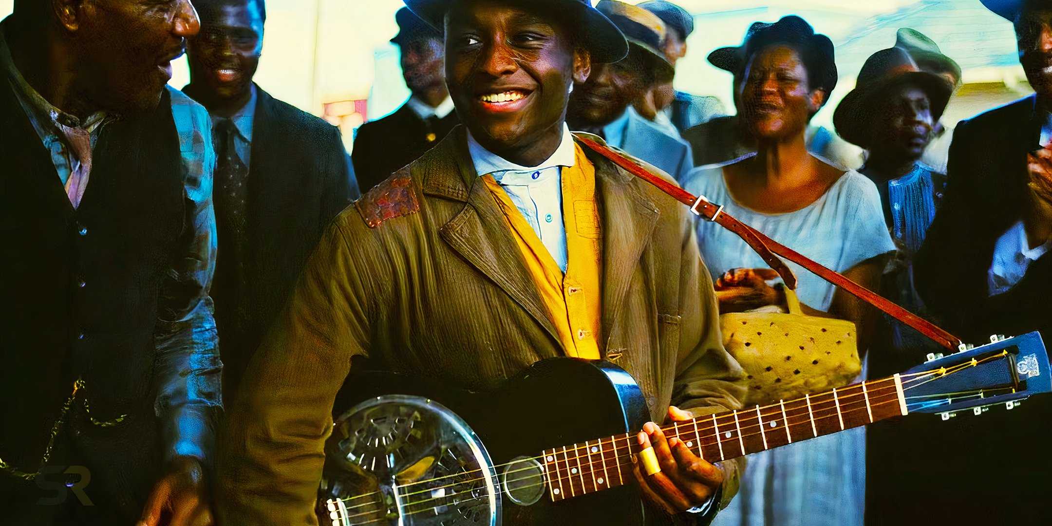 Сэмми играет на гитаре и улыбается в фильме "Sinners"