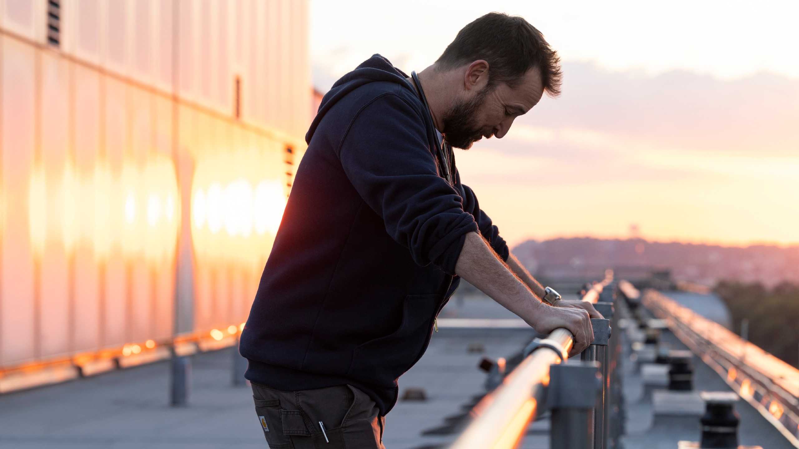 Доктор Робби из The Pitt на крыше, держась за перила.