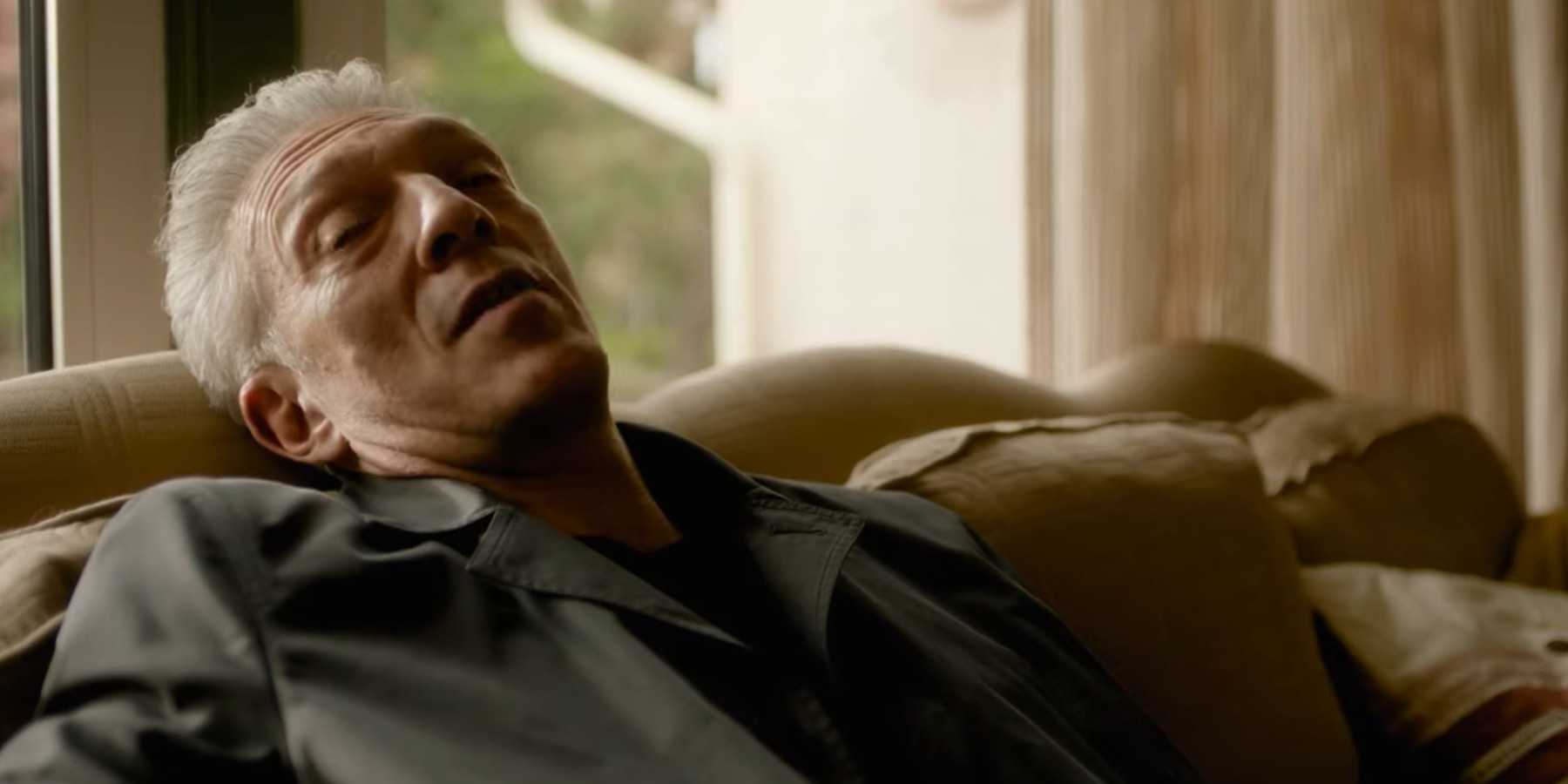 Винсент Кассель, сидящий на диване и выглядящий грустно в фильме "The Shrouds"