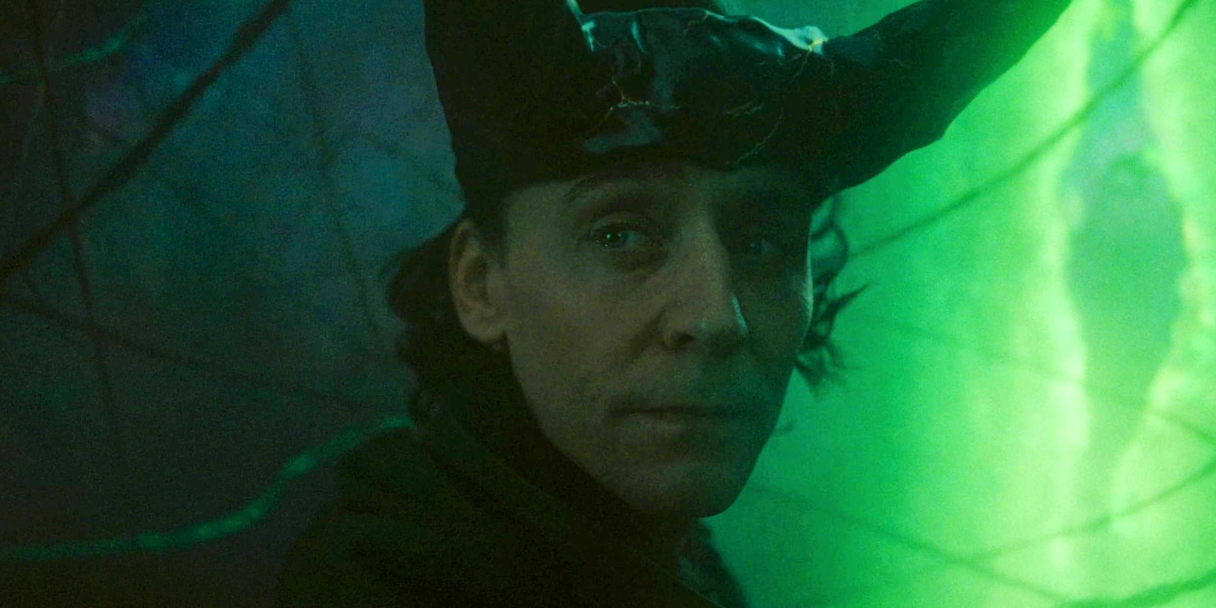 Том Хиддлстон в роли Локи, смотрит в сторону с зеленым разломом мультивселенной на заднем плане в финале 2-го сезона "Локи"