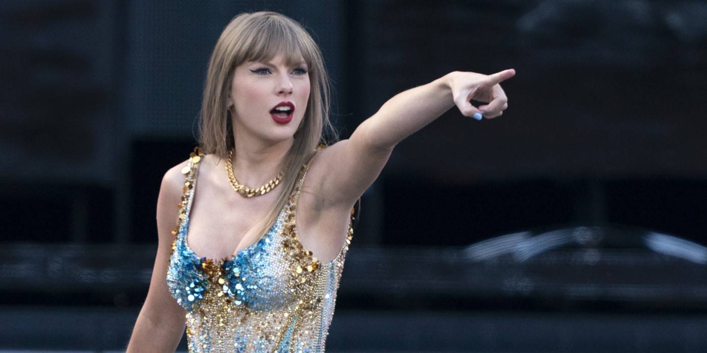 Taylor Swift на сцене, указывающая пальцем.
