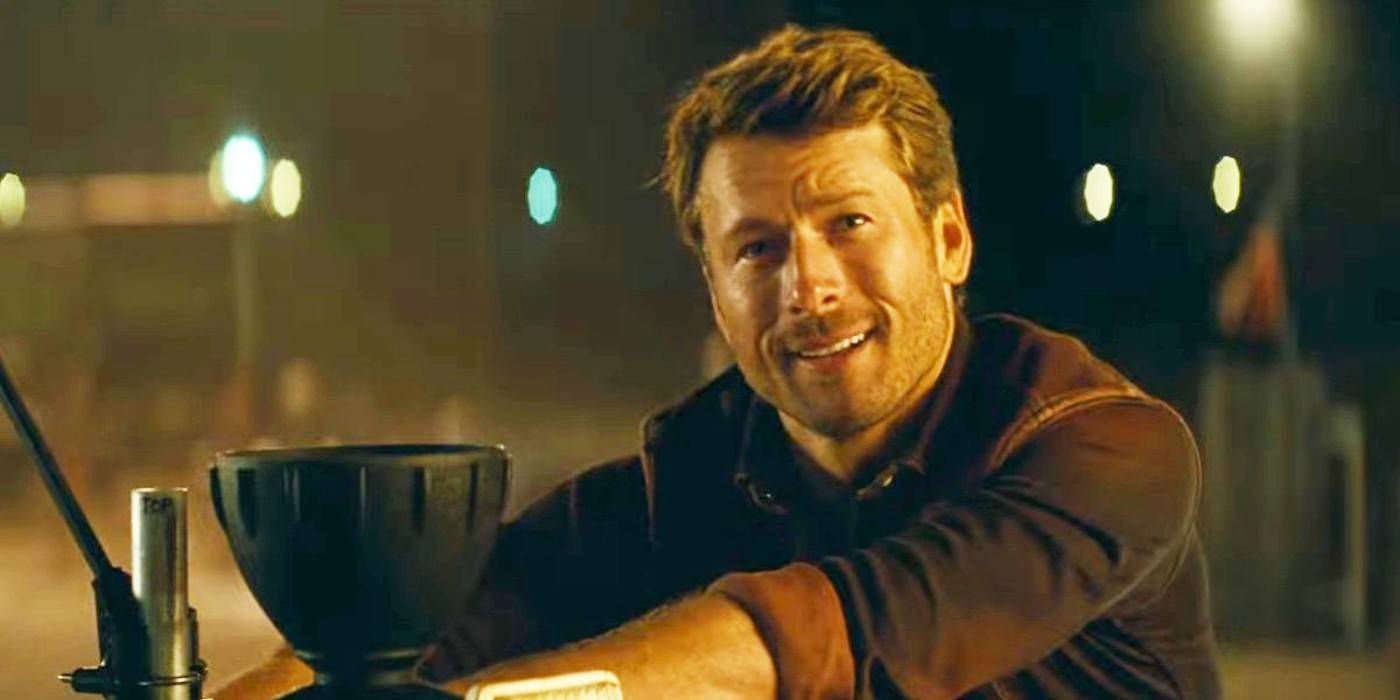 Глен Поуэлл (Тайлр Оуэнс) улыбается, опираясь на свой грузовик в фильме "Твистерс"