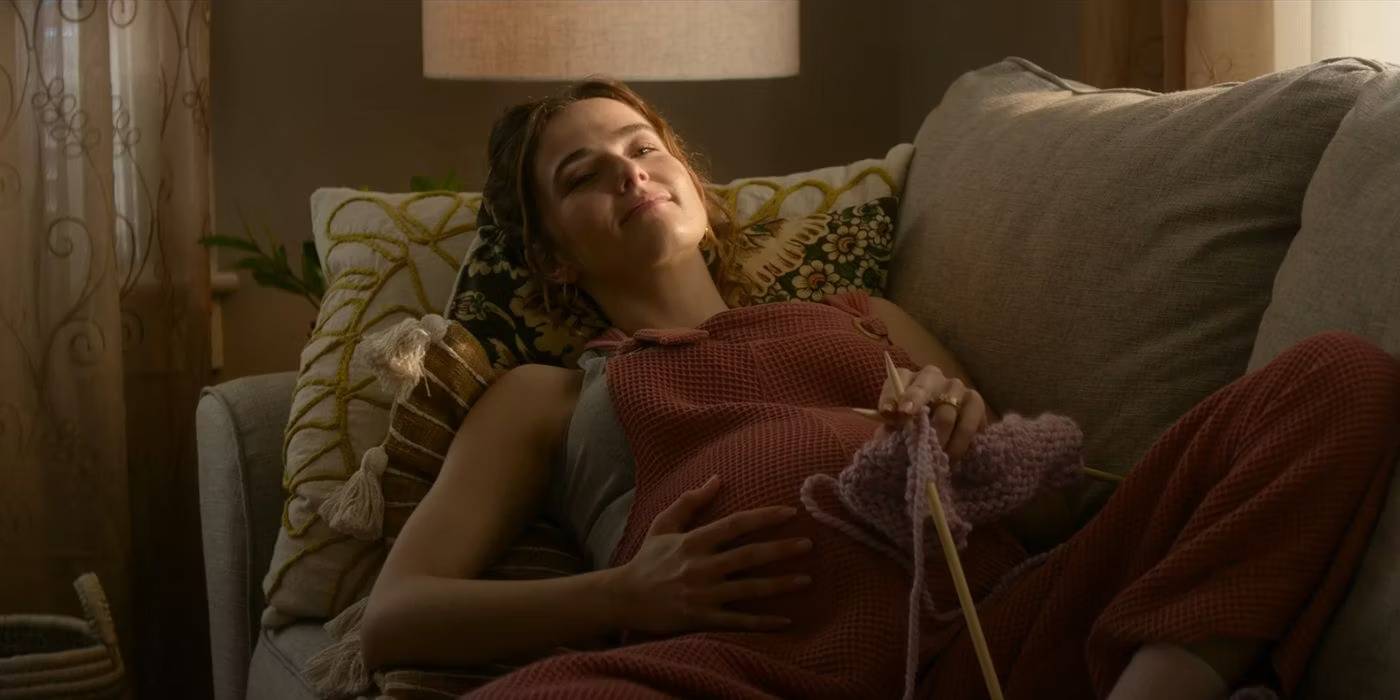 Зои Деуч беременная, улыбающаяся и лежащая на диване в фильме "Juror No. 2"